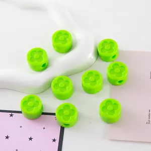Detailed view of bright green acrylic beads with recessed clover pattern for DIY crafts.