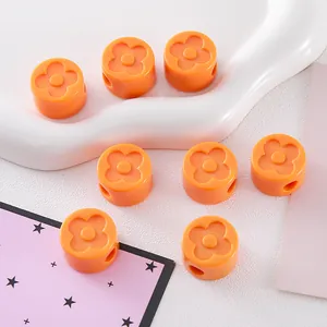 Detailed macro view of orange acrylic clover beads with side holes for DIY crafts