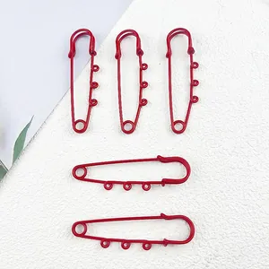 Detail of five red lacquer coated large safety pins with integrated hanging loops for DIY