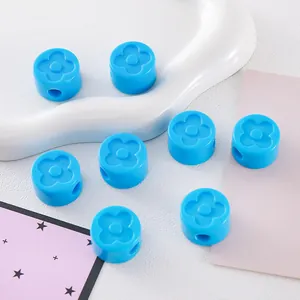 Macro detail of sky blue acrylic cylinder beads with raised four-leaf clover motifs