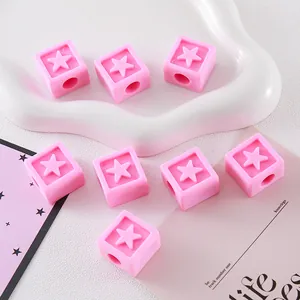 Close-up of pink cubic acrylic beads with embossed star pattern for DIY jewelry crafts.