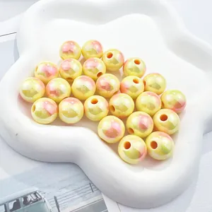 Detailed close-up of iridescent yellow round beads with pink heart patterns for DIY