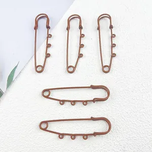 Macro detailed view of brown lacquered large safety pins featuring three small side loops