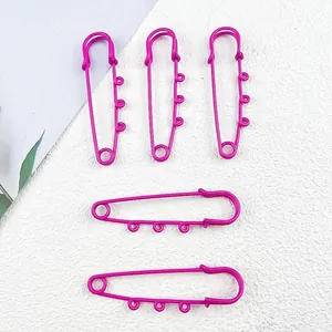 Detail view of large pink painted safety pins with three loops for DIY charms