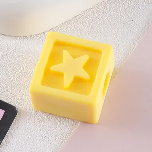 Close-up of a yellow square acrylic bead with an engraved star motif for DIY jewelry.