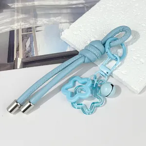 Primer plano de un llavero de cuero azul claro con colgante de estrella y cascabel azul.