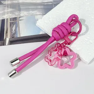 Primer plano de un llavero creativo de cordón de cuero rosa con colgantes de flores