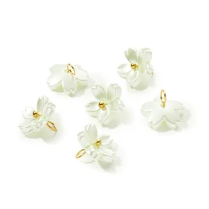 Detail view of iridescent pearl white flower pendants with gold jump rings for DIY jewelry.