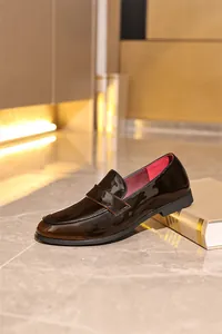 Nahaufnahme hochwertiger brauner Lackleder-Herren-Loafer mit auffälligem rotem Innenfutter.