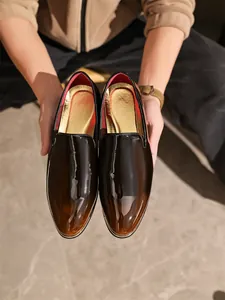 Close-up of men's glossy patent leather slip-on loafers in a brown gradient finish