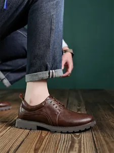 Nahaufnahme brauner Derby-Schuhe aus Leder mit robuster Gummisohle auf Holzboden
