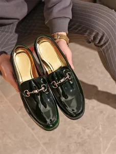 Detailaufnahme dunkelgrüner Lackleder-Loafer mit einer luxuriösen goldenen Trensenschnalle