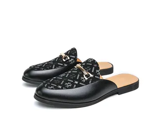 Detalle de mules de cuero negro para hombre sin talón con hebilla metálica y diseño.