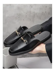 Detalle de zuecos de cuero negro para hombre con una elegante hebilla dorada tipo bocado clásico