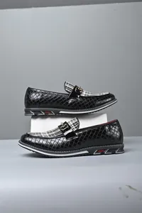 Detalle de mocasines negros trenzados con lengüeta a cuadros y hebilla dorada chic