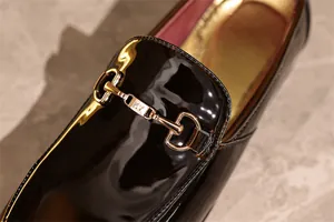 Detailansicht eines glänzenden schwarzen Lacklederschuhs mit goldener Schnalle
