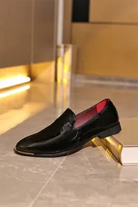 Detail shot of black patent leather men's loafers with gold toe trim and red lining
