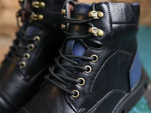 Close-up view of vintage black leather boots featuring bronze eyelets and navy blue accents
