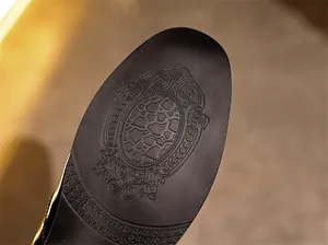 Detailansicht einer Herrenlederschuhsohle mit aufwendig geprägtem heraldischem Muster.