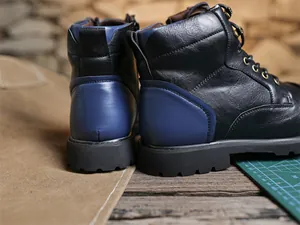 Detailed rear view of black and blue colorblocked retro leather Martin boots for men.