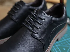 Detailaufnahme von schwarzen Derby-Schuhen aus Leder mit Schnürung und Textur