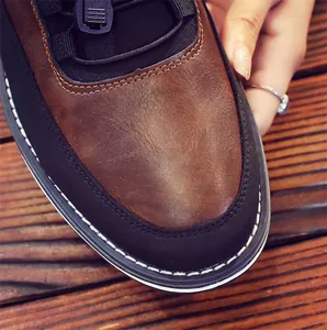 Close-up of men's leather loafer showing brown textured upper and white stitching