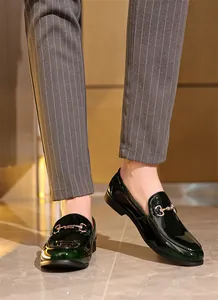 Detailaufnahme von grünen Lackleder-Loafers für Herren mit goldener Trense und Streifenhose.