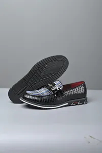 Detalle macro de mocasines negros para hombre con tela a cuadros azul y hebilla metálica