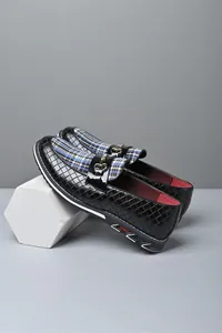 Detalle de mocasines de cuero trenzado negro con panel de cuadros y hebilla