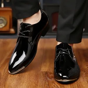 Detailed view of high-gloss black leather pointed-toe men's business dress shoes on wood