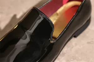 Close-up detail of premium black patent leather loafers showing fine stitching.