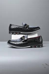 Vista lateral detallada de mocasines de cuero negro con tela a cuadros y hebilla dorada.