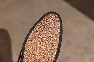 Detailed macro view showing the unique metallic textured finish on a leather business shoe.