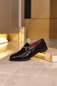 Eleganter bordeauxroter Lackleder-Loafer mit goldener Schnalle auf einem Marmorboden