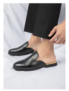 Primer plano de mules de cuero negro para hombre con un detalle de hebilla dorada