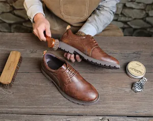 Nahaufnahme von braunen Retro-Herren-Derby-Schuhen beim Polieren auf rustikalem Holz
