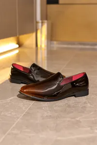 Detail view of premium men's patent leather loafers in dark brown gradient with red lining.
