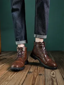 Close-up of men's retro brown leather Martin boots with side zipper and lace-up detail.