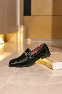 Nahaufnahme von eleganten dunkelgrünen Lackleder-Loafern mit goldener Gebiss-Schnalle