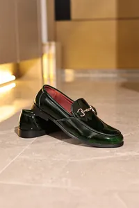 Nahaufnahme von stilvollen dunkelgrünen Lackleder-Loafers mit klassischem Metallelement.
