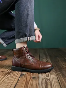 Close-up of men's vintage brown leather high-top Martin boots worn on dark wooden floor