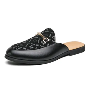 Elegantes mules de cuero negro para hombre con hebilla dorada e inserto de tela con dibujo.
