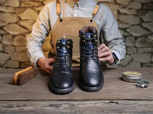 Close-up detail of vintage black leather high-top Martin boots for men in a craftsman workshop