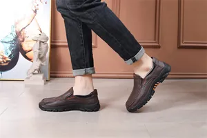 Detail of brown leather slip-on loafers worn while walking in a modern indoor setting