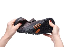 Flexible brown pebbled leather slip-on shoe being bent to show durability
