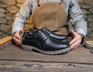 Nahaufnahme von schwarzen Derby-Schuhen aus Leder, gehalten von einem Handwerker