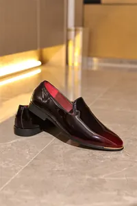 Elegant side view of men's burgundy patent leather loafers featuring gold metal toe accents.