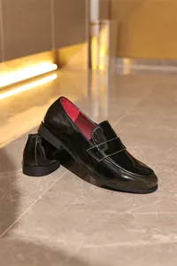 Detaillierte Seitenansicht glänzender schwarzer Lackleder-Loafer mit rotem Innenfutter