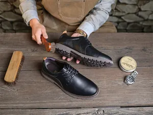 Nahaufnahme von schwarzen Leder-Derby-Schuhen, die mit einer Rosshaarbürste poliert werden