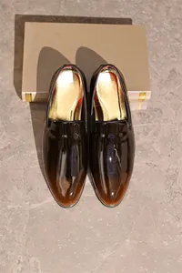 High-angle view of premium glossy gradient brown and black patent leather loafers